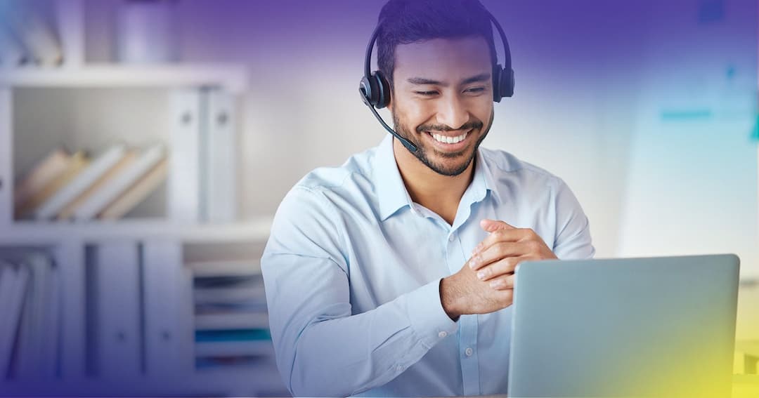 Customer Service agent talking on headset in front of laptop. 